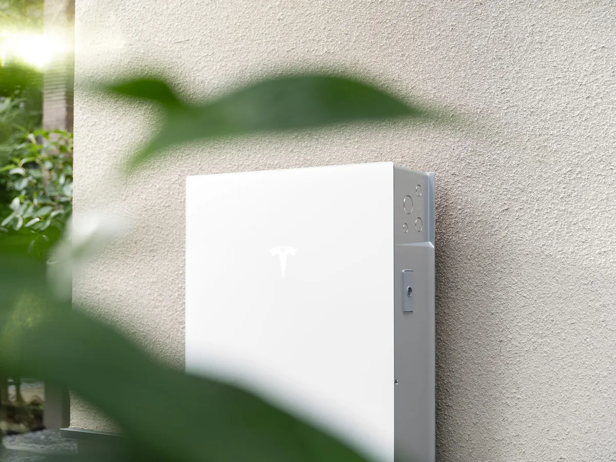 住宅の外壁に設置されたテスラ Powerwall 3 の本体。白いフロントパネルにテスラのロゴ
