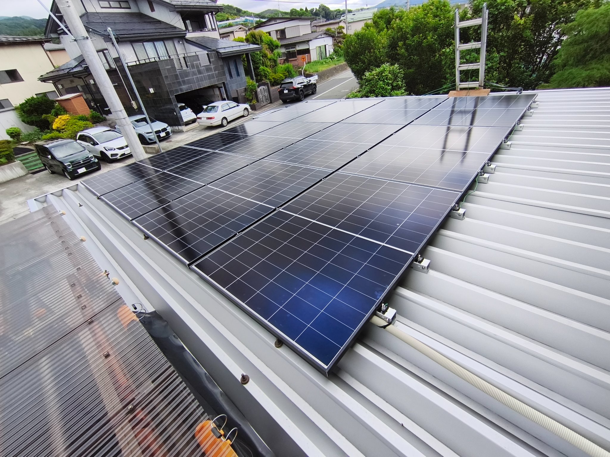 金属屋根に太陽光パネルを施工中の様子。屋根端部の固定金具と離隔が見える