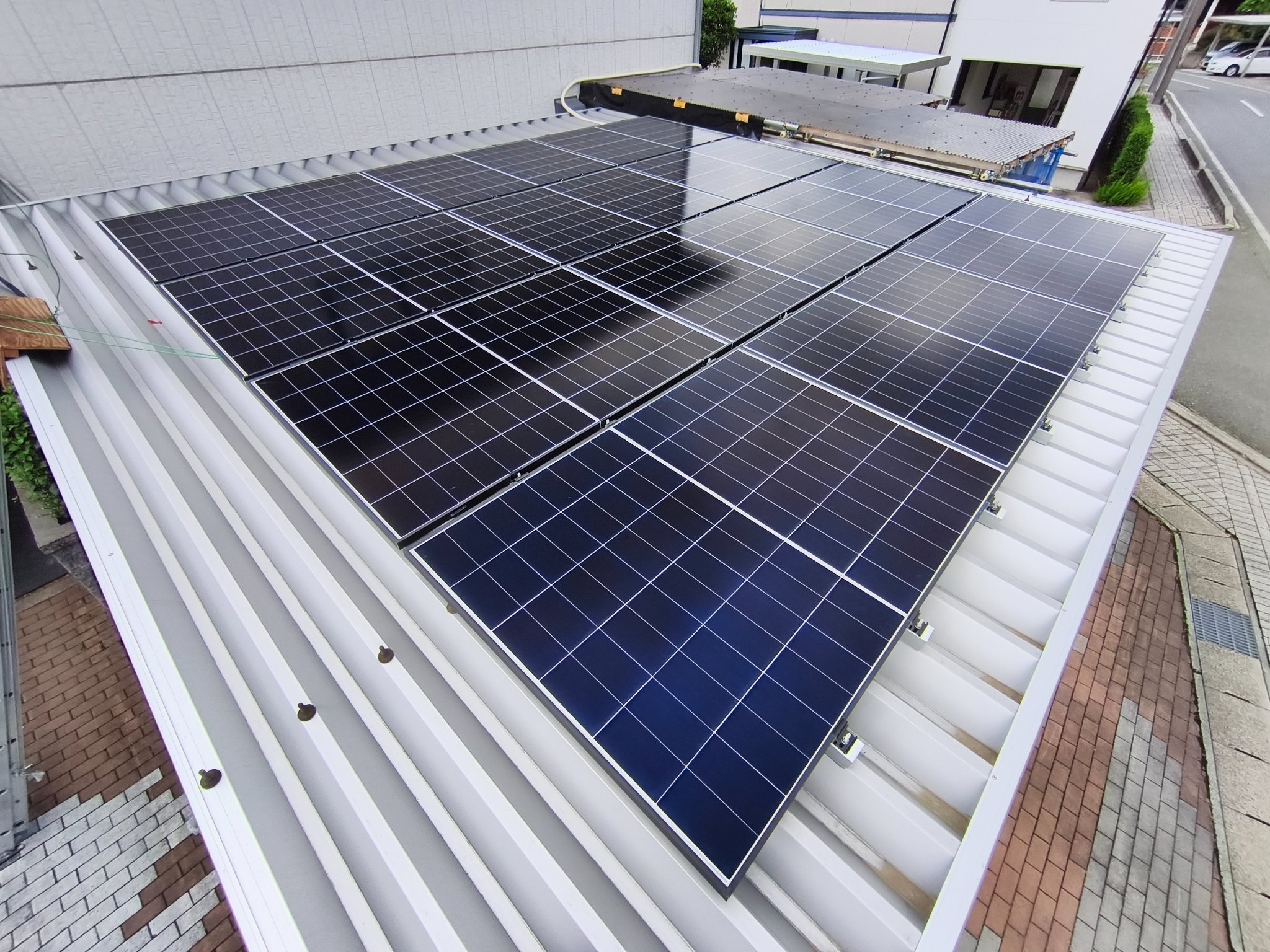 金属屋根に設置された太陽光パネルの俯瞰。端部の固定金具が並ぶ