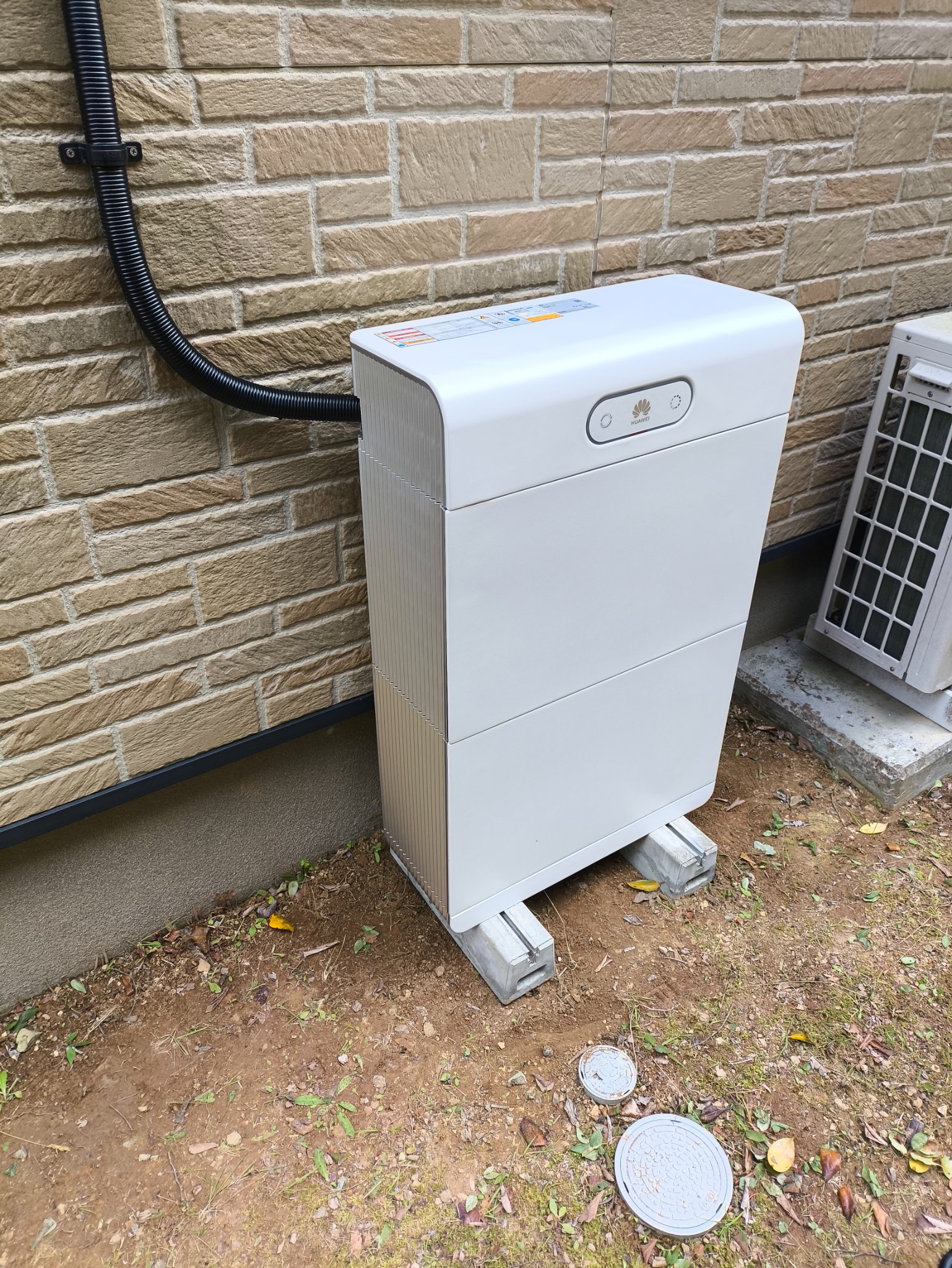屋外の地面に据えた積層型の蓄電池ユニット。隣に室外機がある