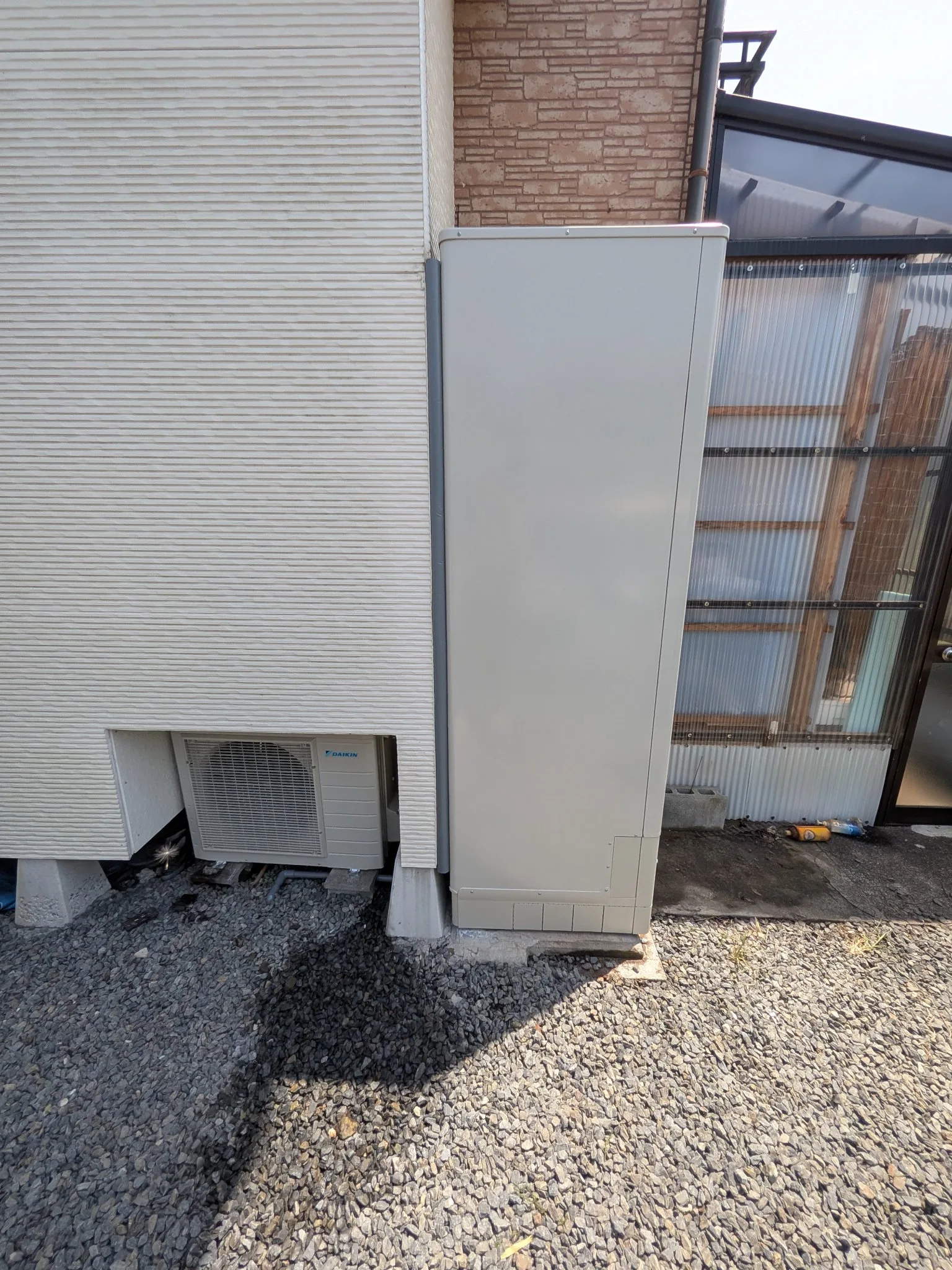 建物のすき間に設置された薄型のエコキュート貯湯タンクとヒートポンプ