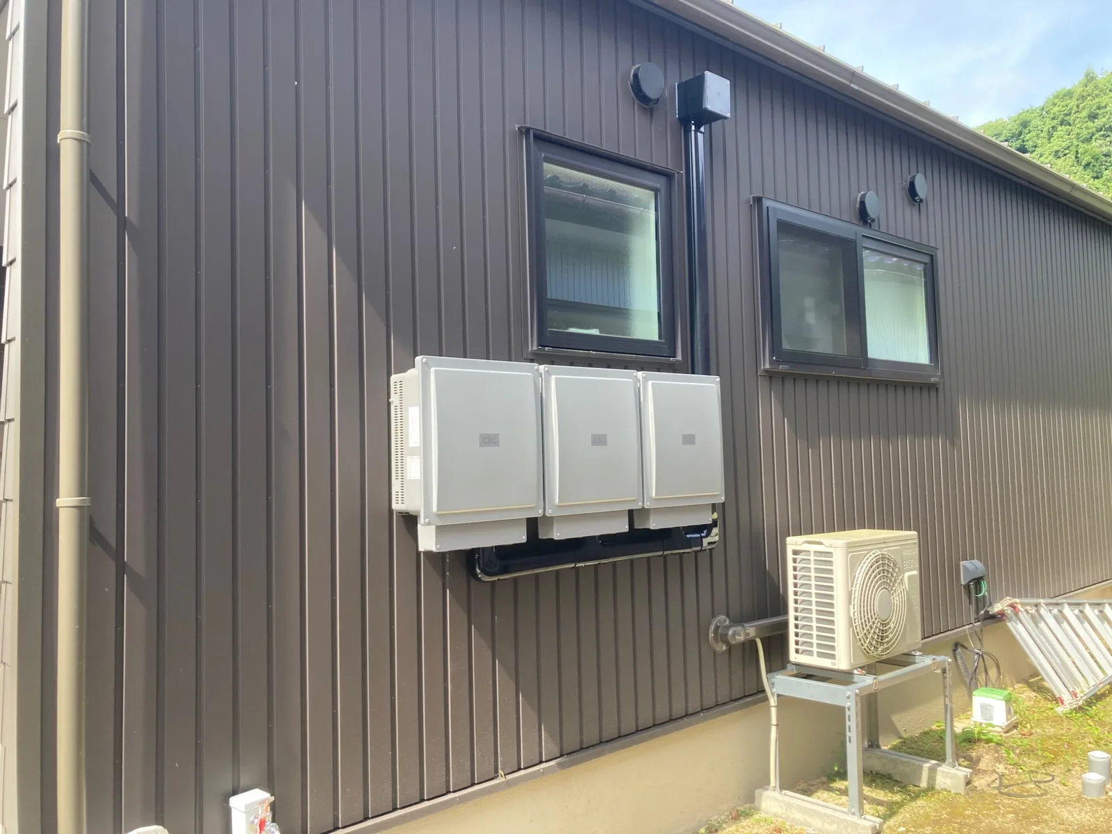住宅の外壁に横並びで設置されたパワーコンディショナ3台と室外機