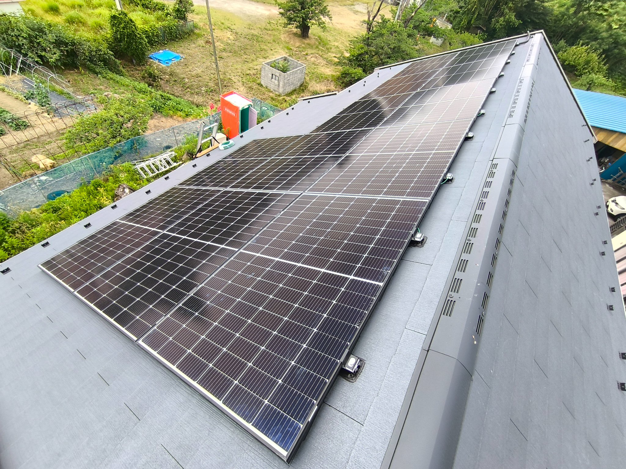 スレート屋根の片面に設置された太陽光パネルの俯瞰。山あいの住宅