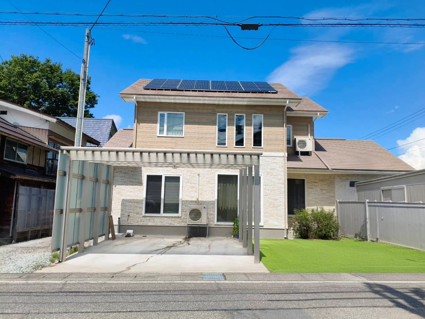 戸建て住宅の外観。屋根に太陽光パネル、敷地にカーポート