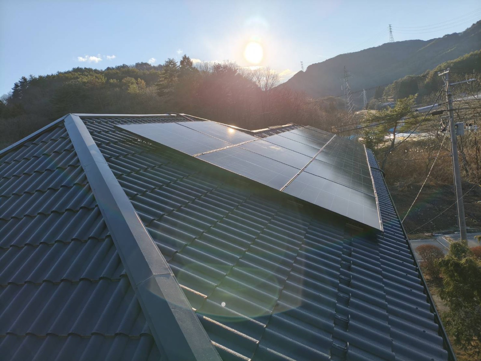 瓦屋根に設置した太陽光パネルと冬の朝日